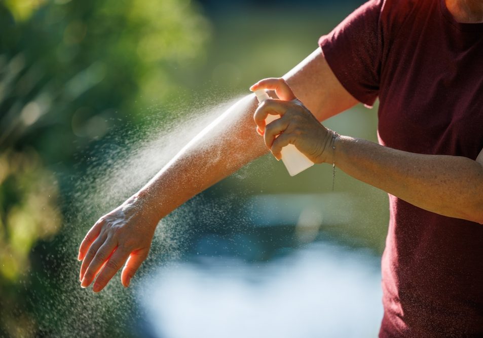 Woman Applying Insect Repellent On Her Arm Outdoors